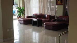 A living room with a sectional sofa, a coffee table, and a potted plant. - Alwaq Hotel (Bahir Dar)