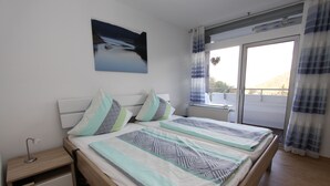 A bedroom with a bed, a nightstand, a window with curtains, and a painting on the wall. - Ferienwohnung Riefenbach (Bad Harzburg)