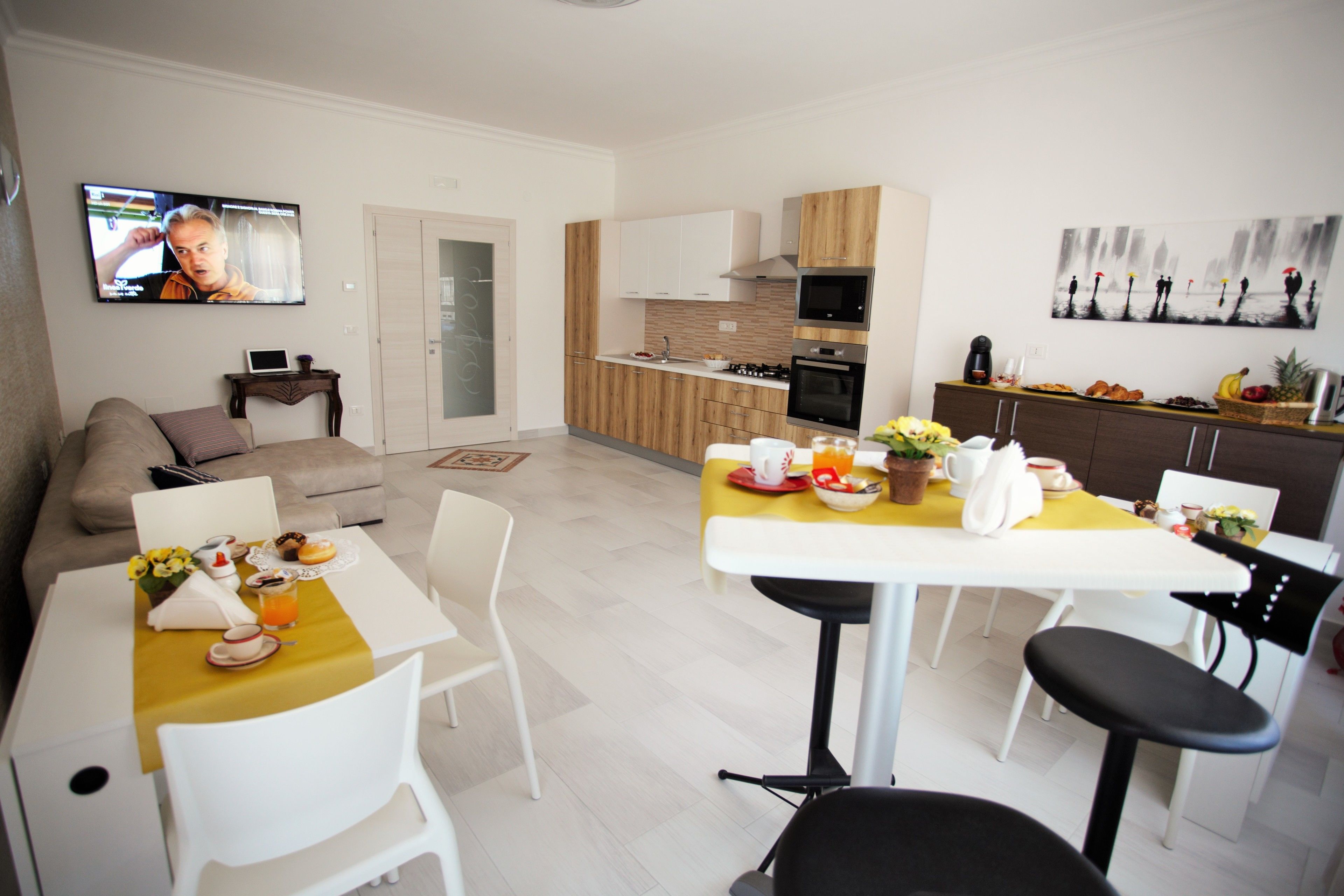 A modern kitchen with a dining area, a TV, and a living room with a sofa.