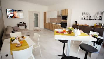 A modern kitchen with a dining area, a TV, and a living room with a sofa.