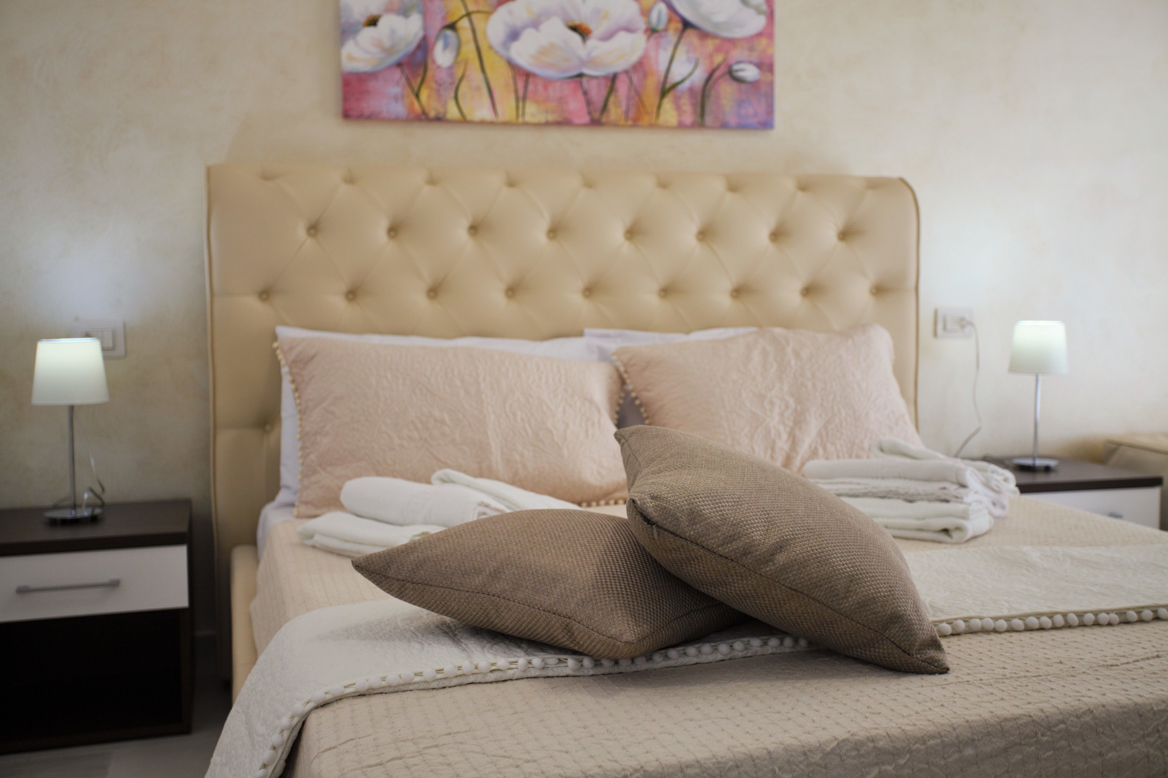 Una cama bien tendida con un cabecero capitonado, dos almohadas y una colcha.