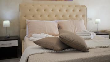 Una cama bien tendida con un cabecero capitonado, dos almohadas y una colcha.