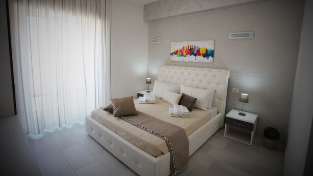 Un dormitorio moderno con una cama grande, una mesita de noche con lámpara y una obra de arte en la pared.