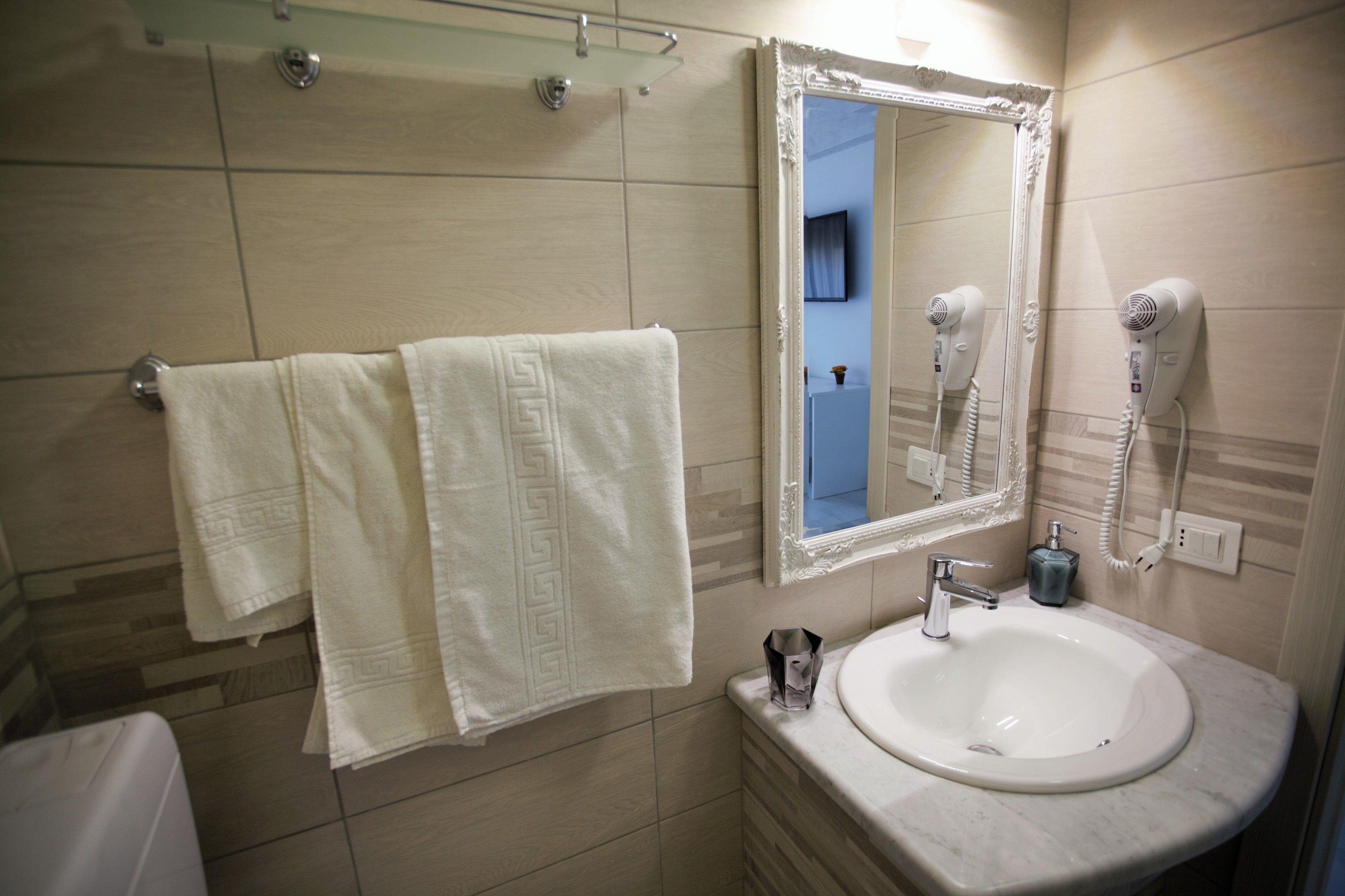 A bathroom with a white sink, two towels, a mirror, and a hairdryer.