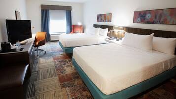 A hotel room with two beds, a TV, a desk, and a chair.