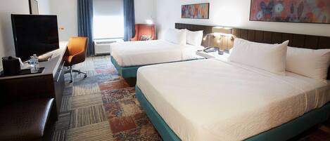 A hotel room with two beds, a TV, a desk, and a chair.