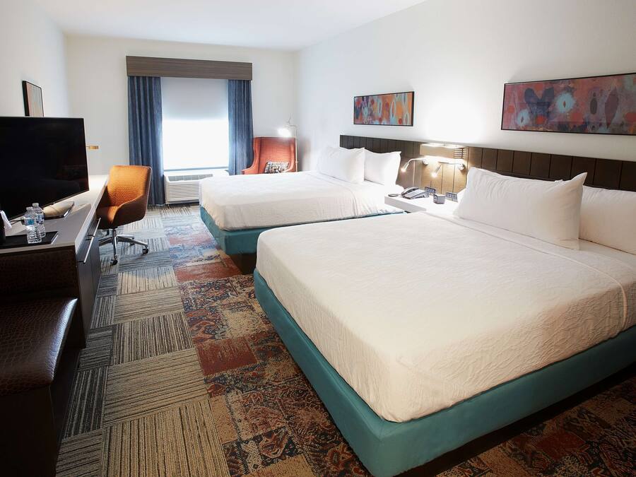 A hotel room with two beds, a TV, a desk, and a chair.