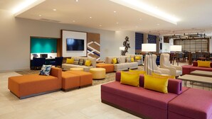 A modern hotel lobby with multiple seating areas, a reception desk, and a large screen. - Hilton Garden Inn Elizabethtown, KY (Elizabethtown)