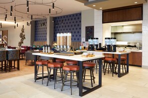 A modern kitchen area with bar stools, a coffee station, and a seating area with tables and chairs. - Hilton Garden Inn Elizabethtown, KY (Elizabethtown)