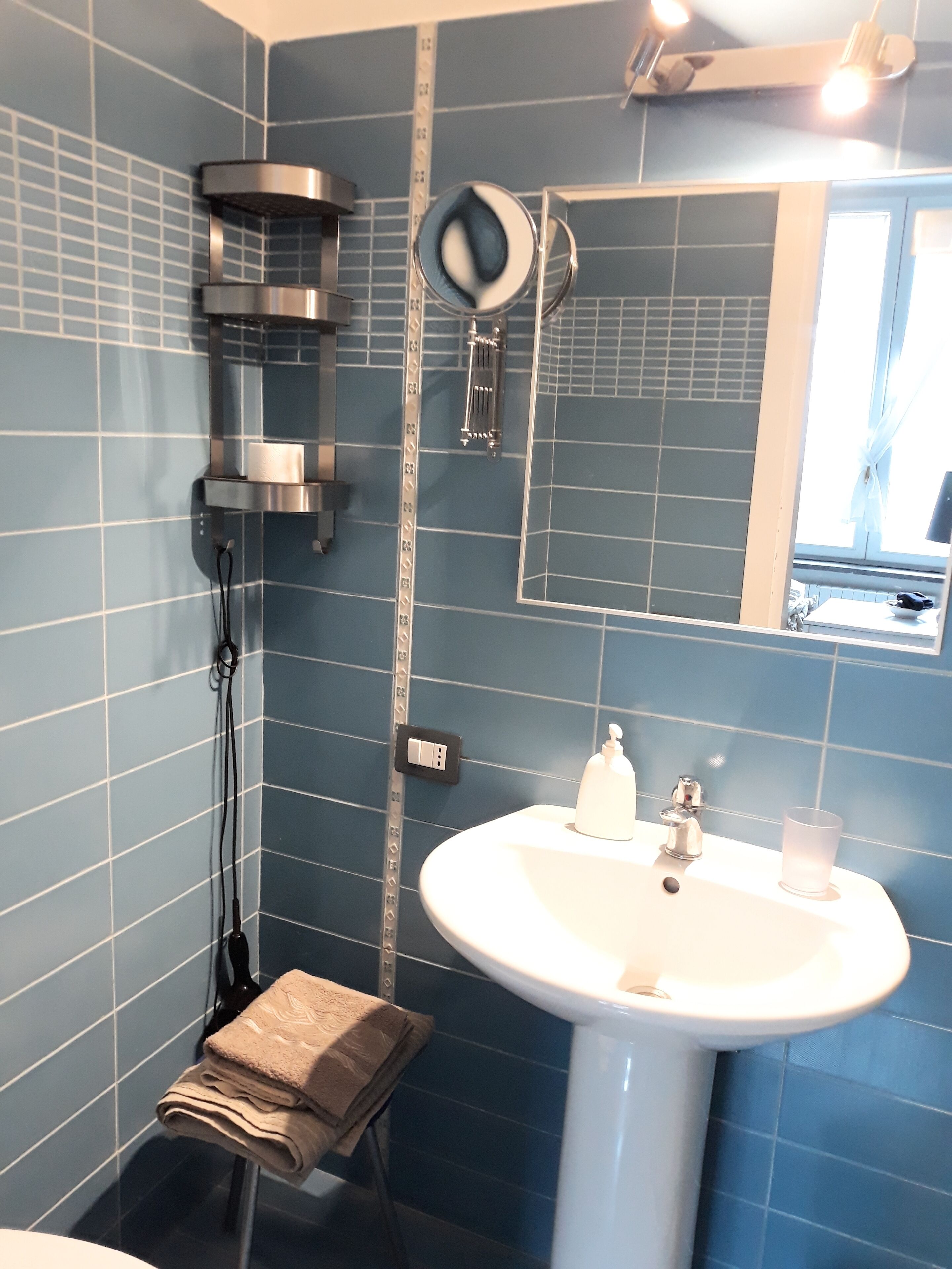 A bathroom with a sink, mirror, towel rack, and shower.