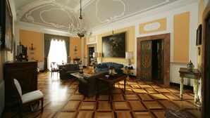 Amplia sala de estar con suelo de parquet estampado, una araña, un sofá y una mesa de centro.