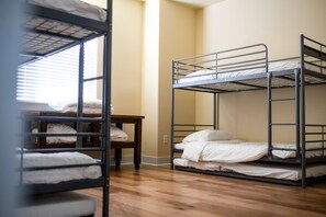 Two comfortable beds with mattresses and pillows, a small table, and a window with blinds.
