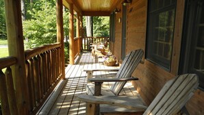 Une terrasse en bois, agrémentée de chaises longues et d’une table, le tout entouré d’une rambarde en bois.