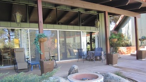 Un espace extérieur aménagé en patio, avec un foyer, des sièges et des plantes en pot.