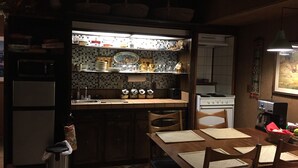 Une cuisine avec un mur recouvert de carreaux, une cuisinière et un coin repas comprenant une table et des chaises.