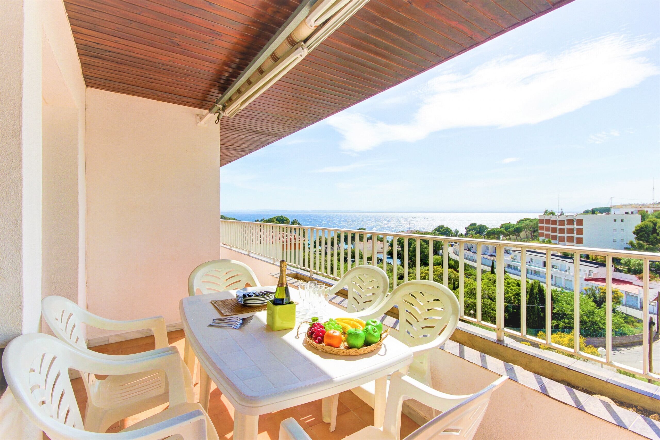 A balcony with a table set for two, a bottle of champagne, and a fruit basket.
