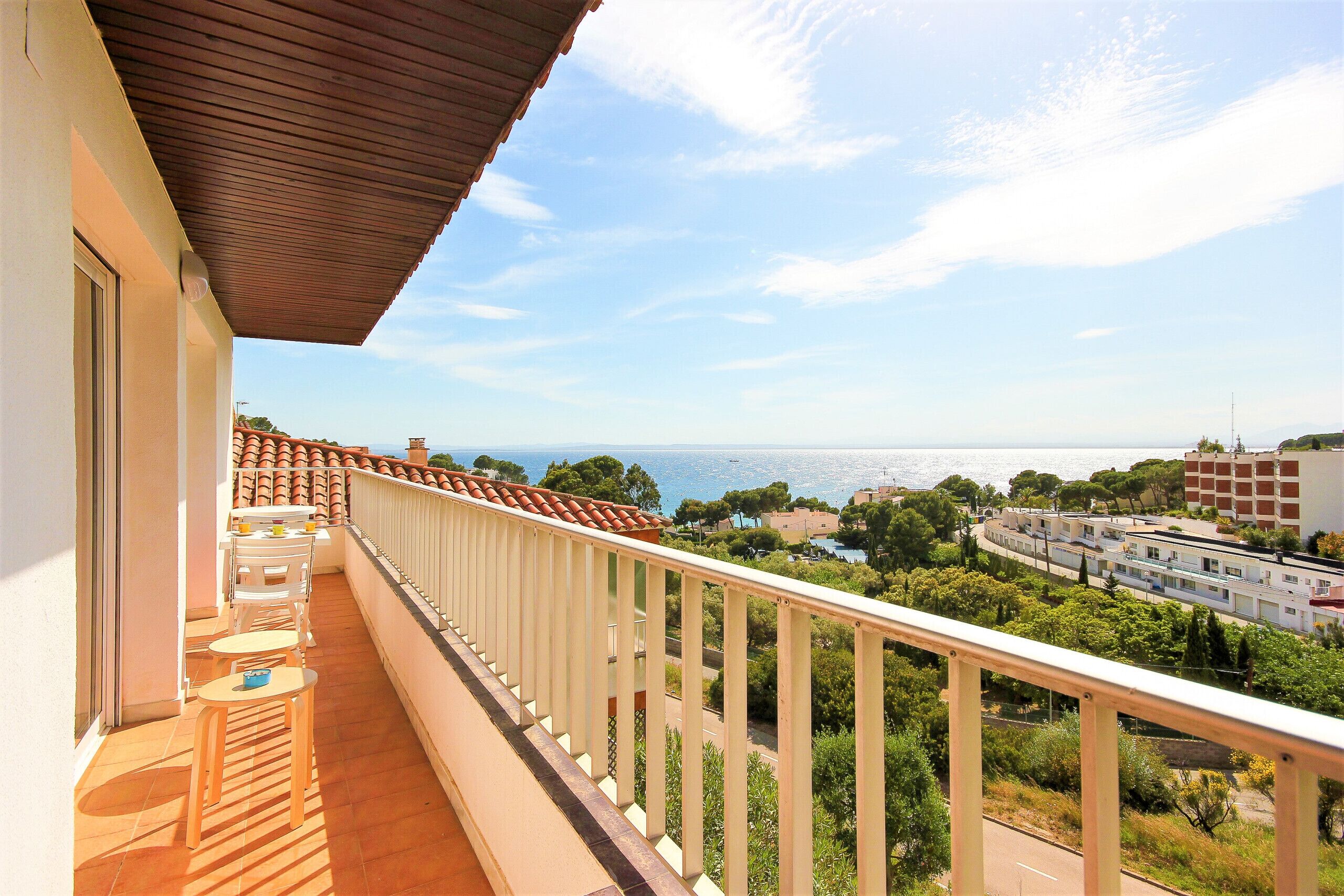 A balcony with a view of the sea, a tiled floor, and a railing.