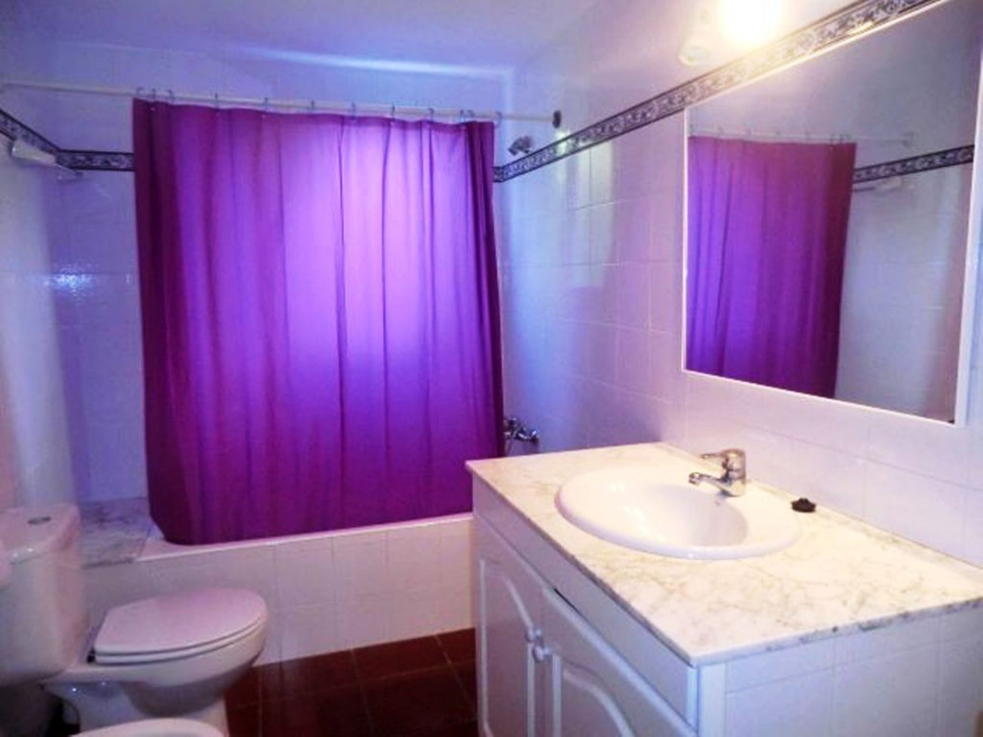 A bathroom with a white sink, a toilet, and a shower curtain.