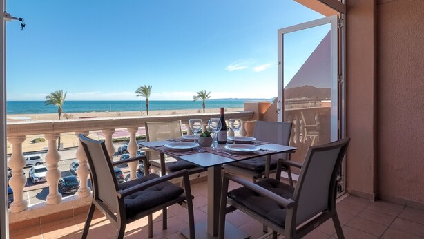 Varanda com mesa posta para dois, com vista para a praia e oceano.