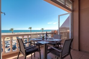 Un balcón con una mesa para dos, con vista a la playa y el océano.