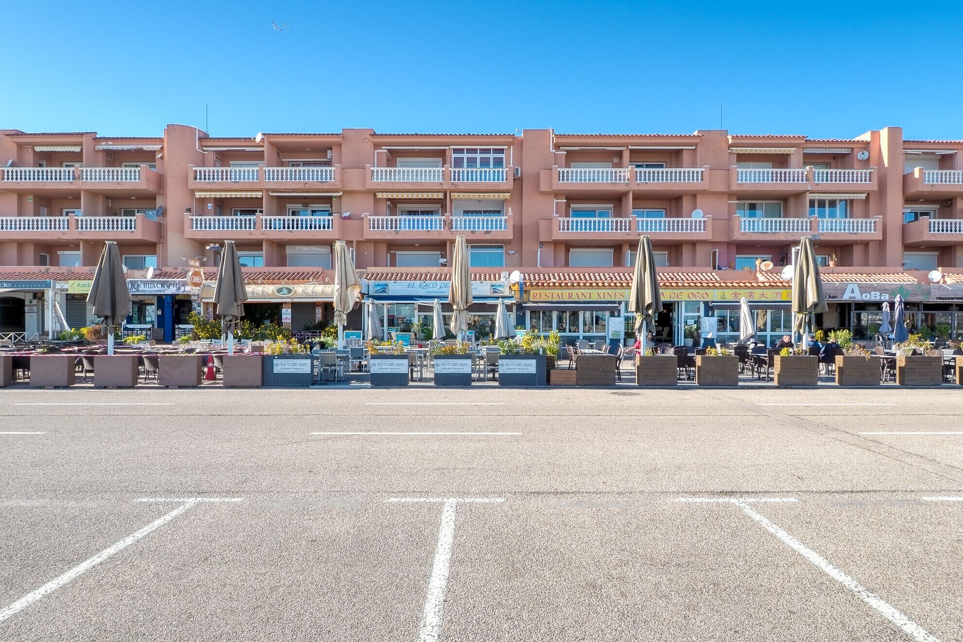 A multi-story hotel with outdoor seating areas and a parking lot.