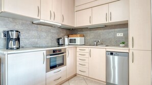 Uma cozinha moderna com cafeteira, micro-ondas, forno e máquina de lavar louça.