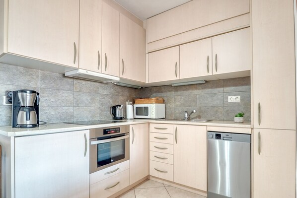 Una cocina moderna equipada con cafetera, microondas, horno y lavavajillas.