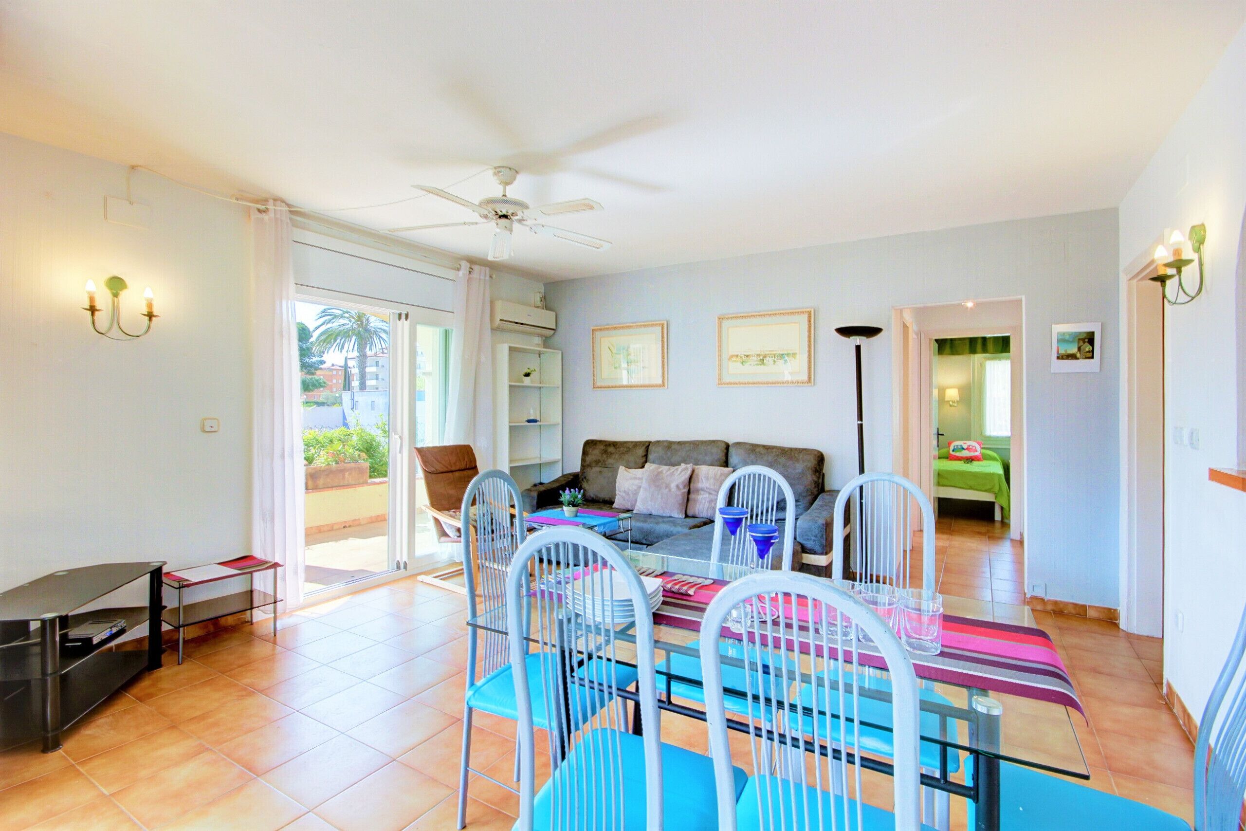 A spacious living area with a dining table, chairs, a sofa, and a ceiling fan.