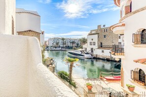 A canal with a boat, buildings, and a white wall. - ISLA CARTAGO 49 Empuriabrava (Empuriabrava)