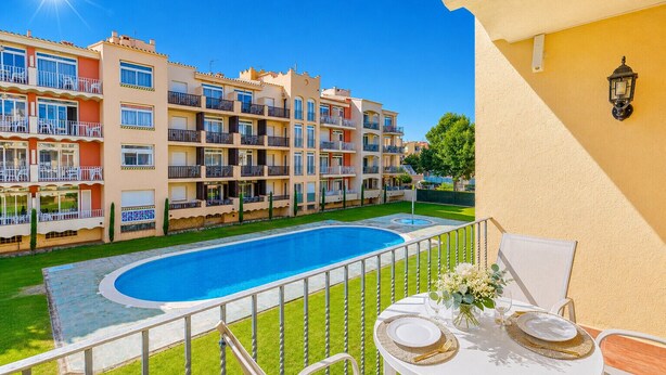 A residential building with a swimming pool, balconies, and a dining area with outdoor furniture.