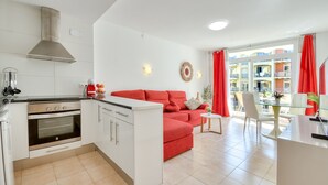 A modern kitchen with a stove, oven, and a red sofa in the living area.