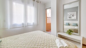 A bedroom with a bed, a large mirror, and a window with curtains.