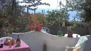 Un patio con una mesa preparada para dos, una silla blanca y una silla reclinable.