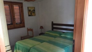 Un dormitorio con cama, una silla, un escritorio y un cuadro en la pared.