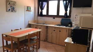 Una cocina compacta con una mesa de madera, sillas, un fregadero, una estufa y un microondas.