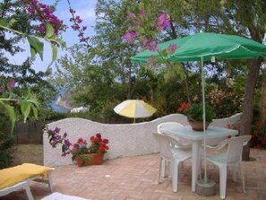 An outdoor patio with a table and chairs, a green umbrella, and potted plants. - Villetta Capo Vaticano Tropea 400 metri dal Mare  " LIMONCELLO " (Capo Vaticano)