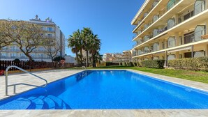 A swimming pool with a clear blue water, surrounded by a stone deck. - MILENI 1 1 4 3 Roses (Rosas / Roses)