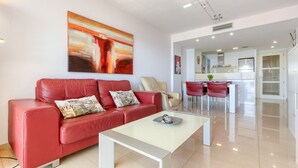 A modern living room with a red leather sofa, a glass coffee table, and a painting on the wall. - MILENI 1 1 4 3 Roses (Rosas / Roses)