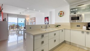 A modern kitchen with a large island, stainless steel appliances, and a view of the sea. - MILENI 1 1 4 3 Roses (Rosas / Roses)