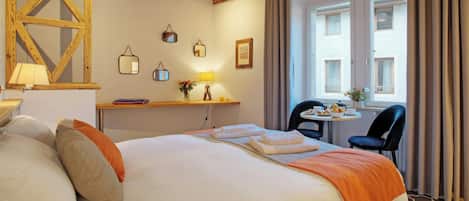 Habitación de hotel con cama, mesita de noche, lámpara y vista al exterior a través de una ventana.
