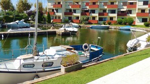 A marina with boats docked, a building with balconies, and a well-maintained grassy area. - PORT SOTAVENT 2A (Empuriabrava)