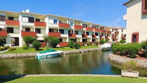 A row of multi-story buildings with balconies, a canal, and a boat docked by the water. - PORT SOTAVENT 2A (Empuriabrava)