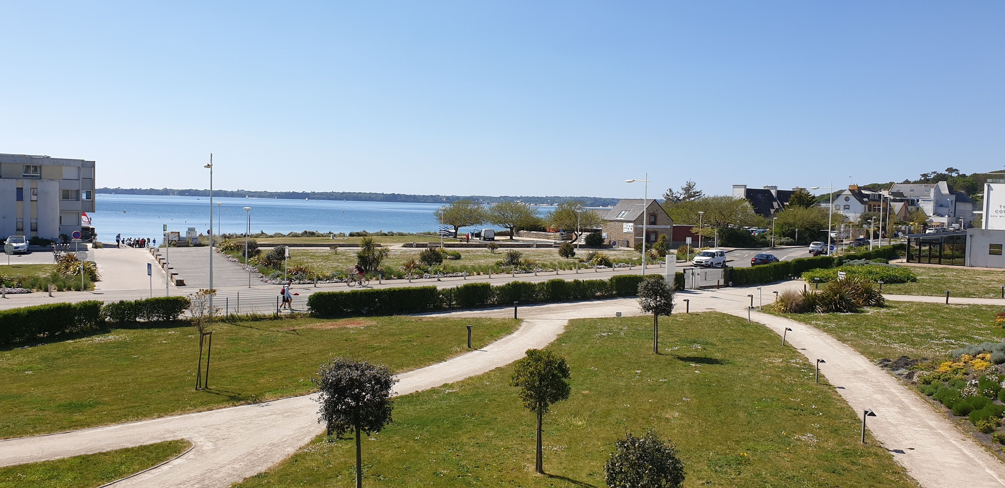 A coastal view with a clear sky, a pathway, and a body of water.