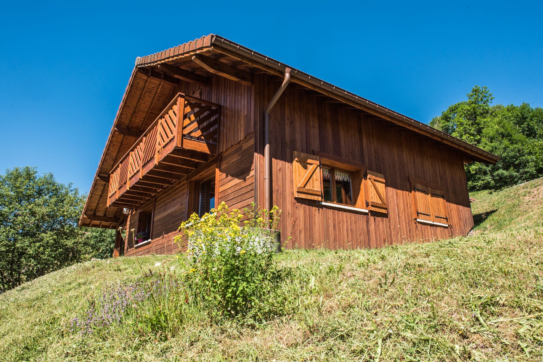 Een houten chalet met een balkon, gelegen op een grasheuvel.