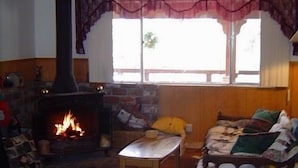 Una sala de estar acogedora con chimenea, un sofá, una mesa y un edredón acolchado.