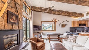 A spacious living room with a fireplace, comfortable seating, a dining area, and a kitchen.