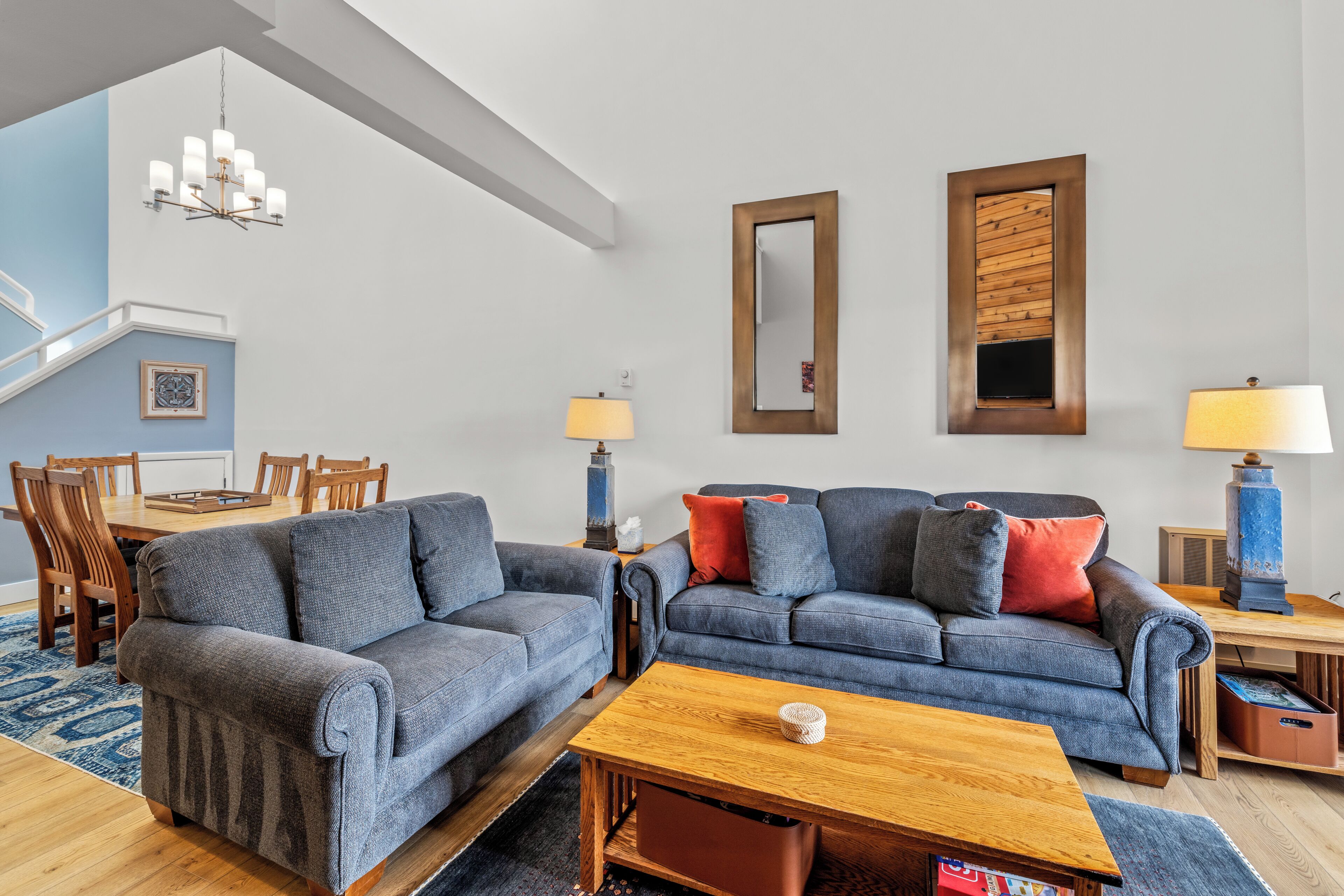 A living room with two grey sofas, a wooden coffee table, and a chandelier.