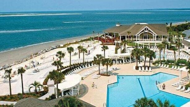 A resort with a large pool, beach area, and ocean view.