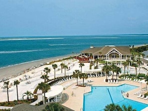 A resort with a large pool, beach access, and a building with a roof.