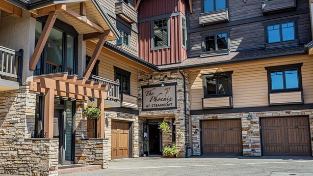 A multi-story building with a stone facade, a sign reading "The Phoenix at Steamboat," and a large entrance with a covered porch. - Cozy 2-Bedroom Ground-Floor Condo at The Phoenix – Steps from the Slopes! (Steamboat Springs)